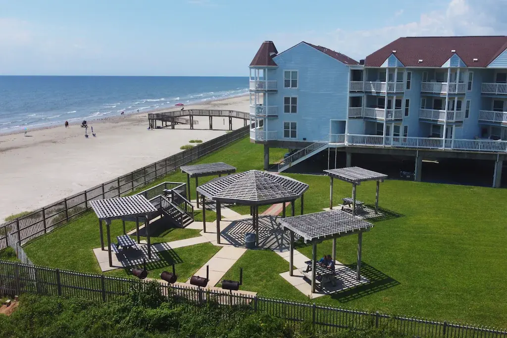 Beachfront lawn with shaded picnic pergolas at the Seascape complex near Condo 2208