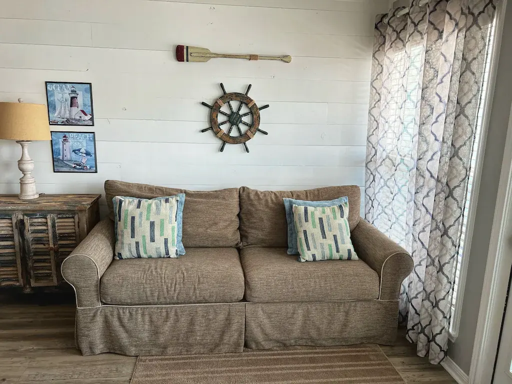 Nautical living room at Seascape Condo 2308 with ship wheel and tan sofa