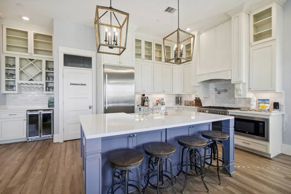 White kitchen with blue island, industrial barstools, and wine bar at Dorado Grande