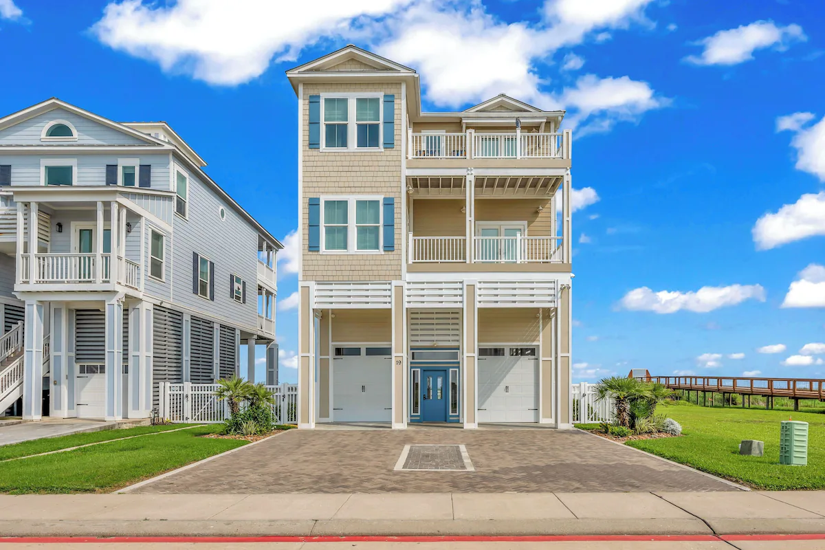 Front exterior of Sandy Sea-cret with blue door, covered parking and paver driveway