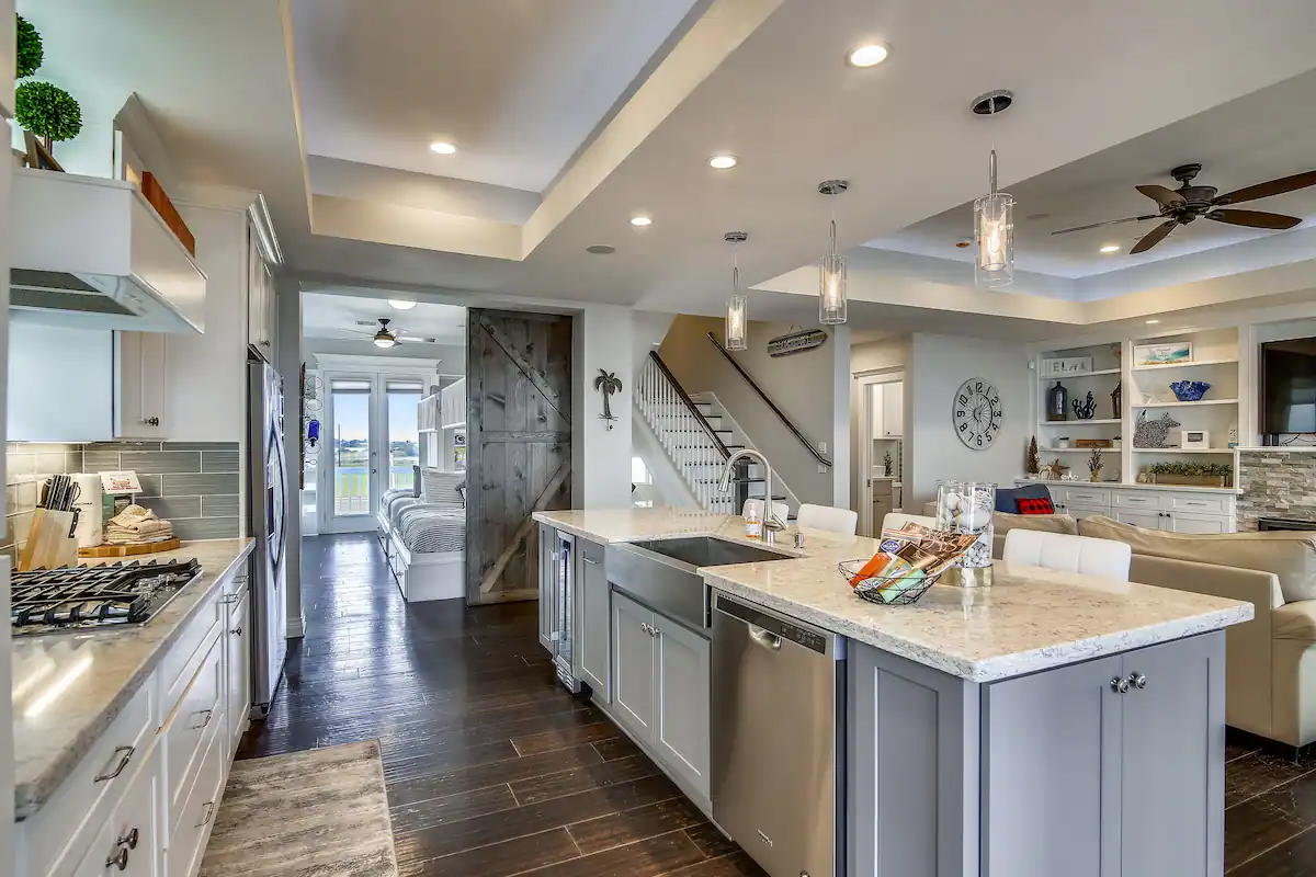 Gourmet kitchen with long quartz island, farmhouse sink, and barn door at Sunrise on the Beach